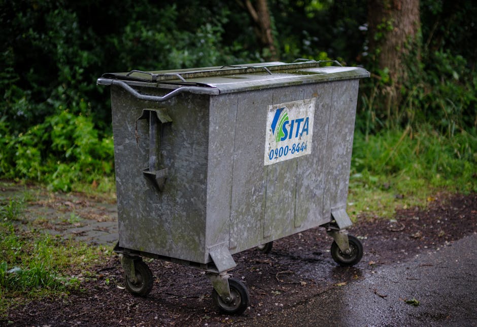 A pile of discarded household debris and waste materials, including wooden slats and frames, an old damaged microwave or small appliance, and various broken or torn pieces of furniture and plastic obj
